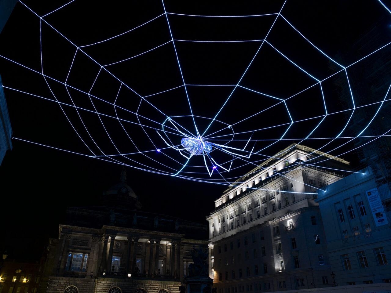 A giant LED lit web hanging above Liverpool's Exchange Flags, with a crystal-studded spider in the center.