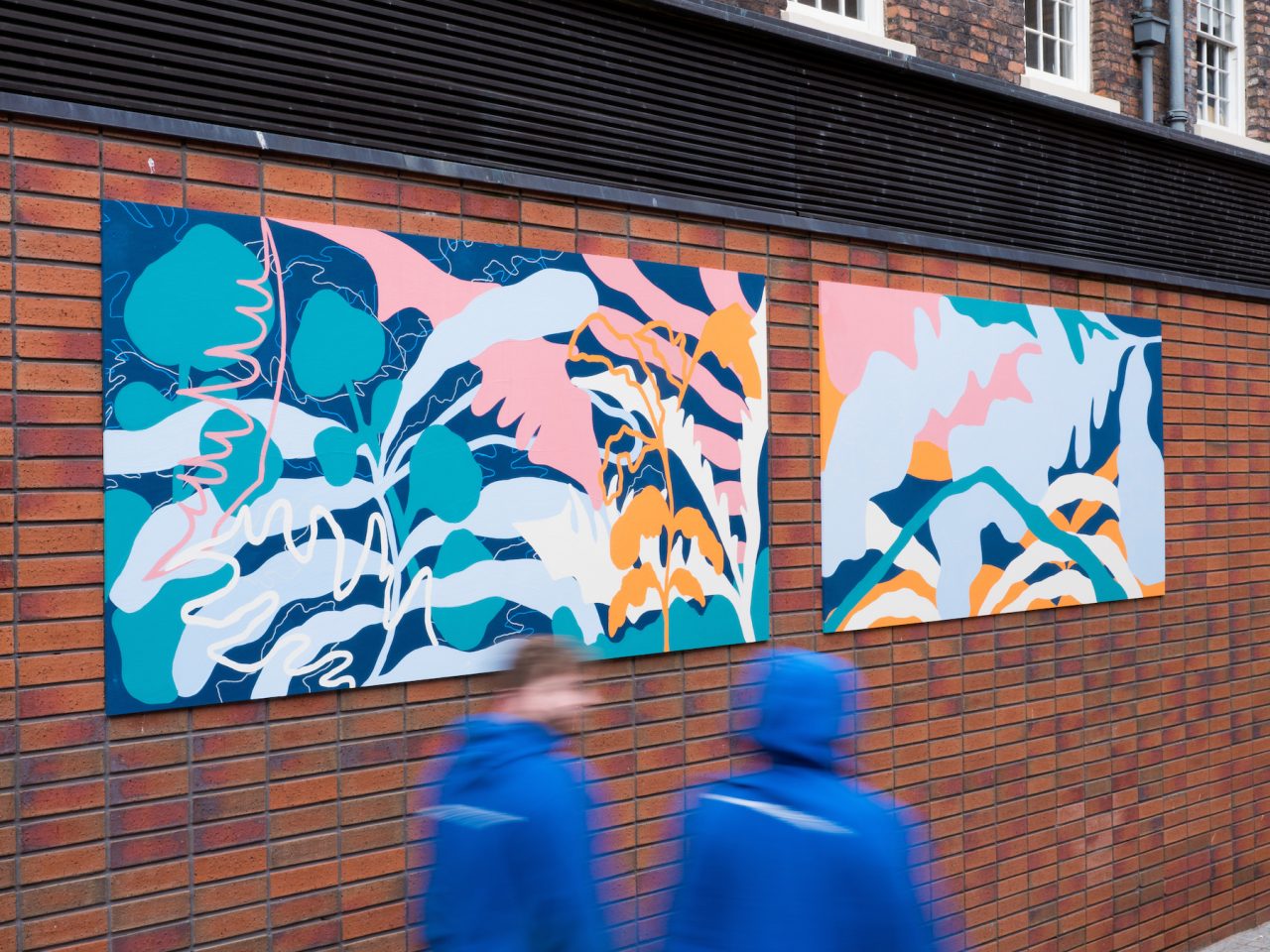 Two large prints on an outside brick wall. The prints are brightly coloured illustrations of plants overlapping eachother.