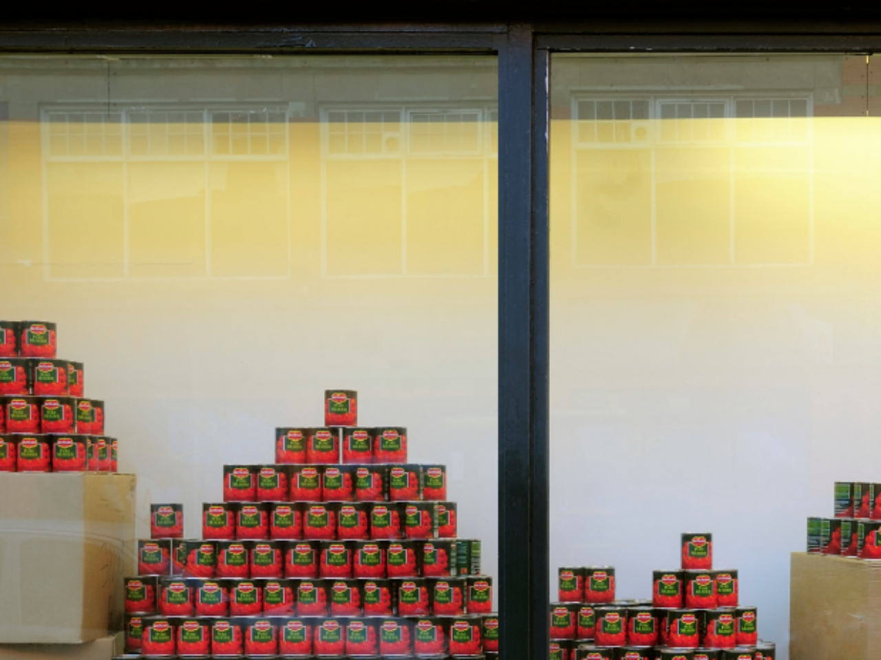 Stacked in large groups, are tinned tomatoes in a window display