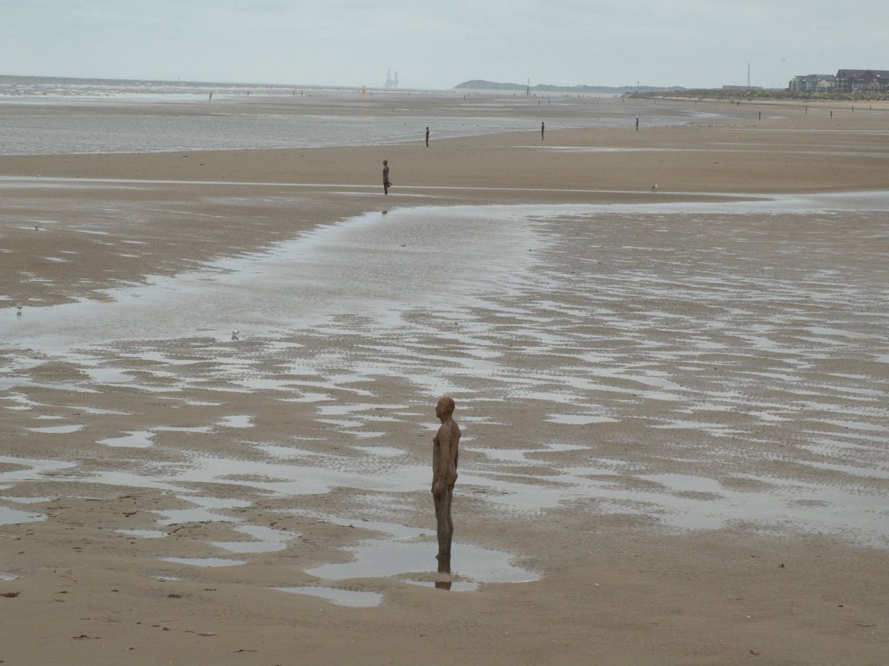 A beach scape with multiple life-size cast-iron moulds of the artists own body
