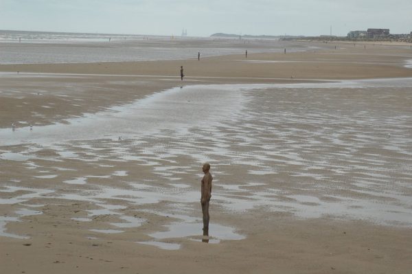 A beach scape with multiple life-size cast-iron moulds of the artists own body