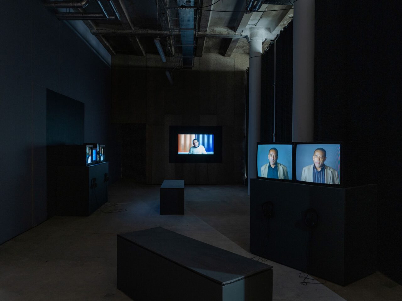 A dark room with multiple screens of different sizes in it, showing excerpts from a filming process⁠.